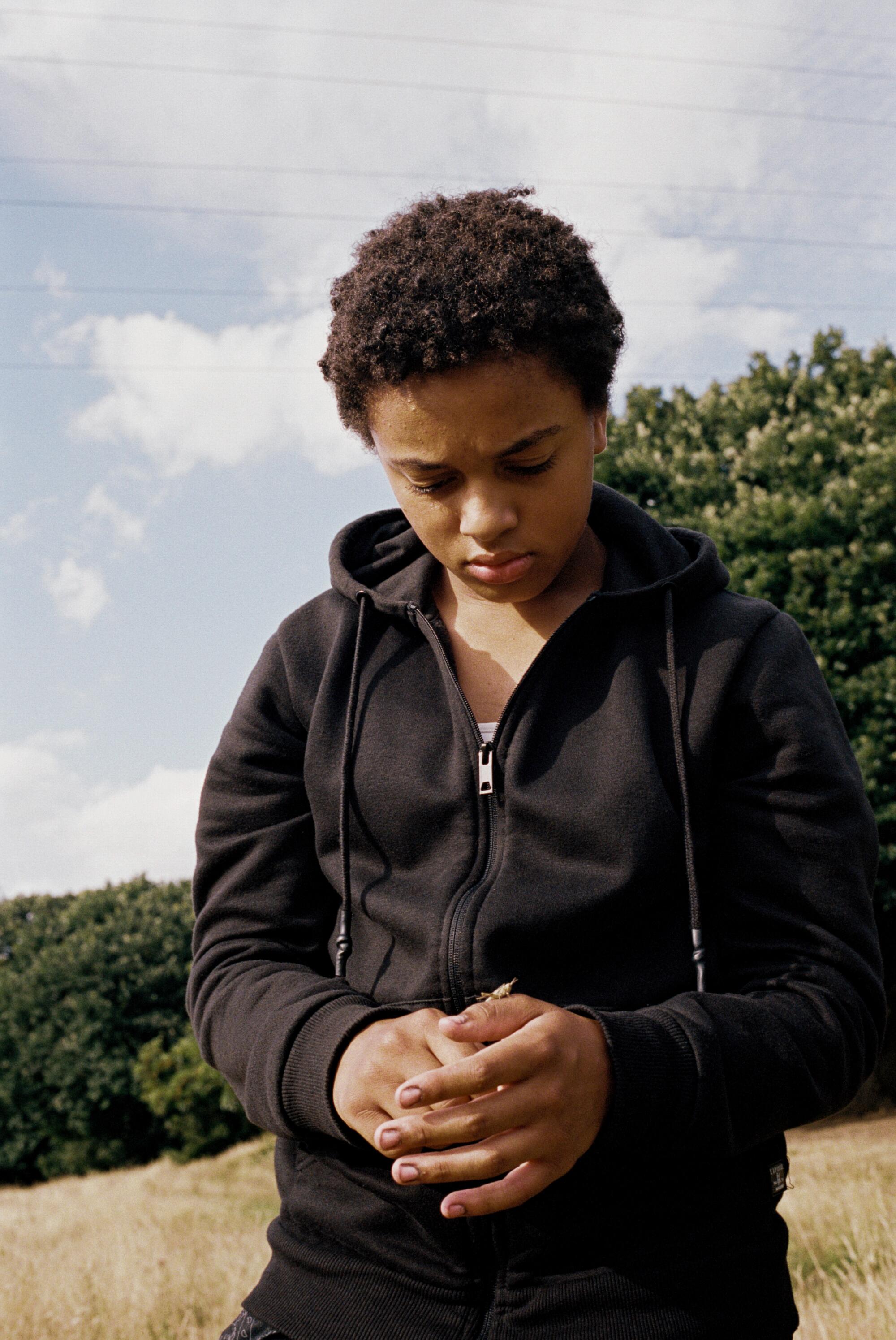 A preteen girl walks outside looking down in the movie "Bird."