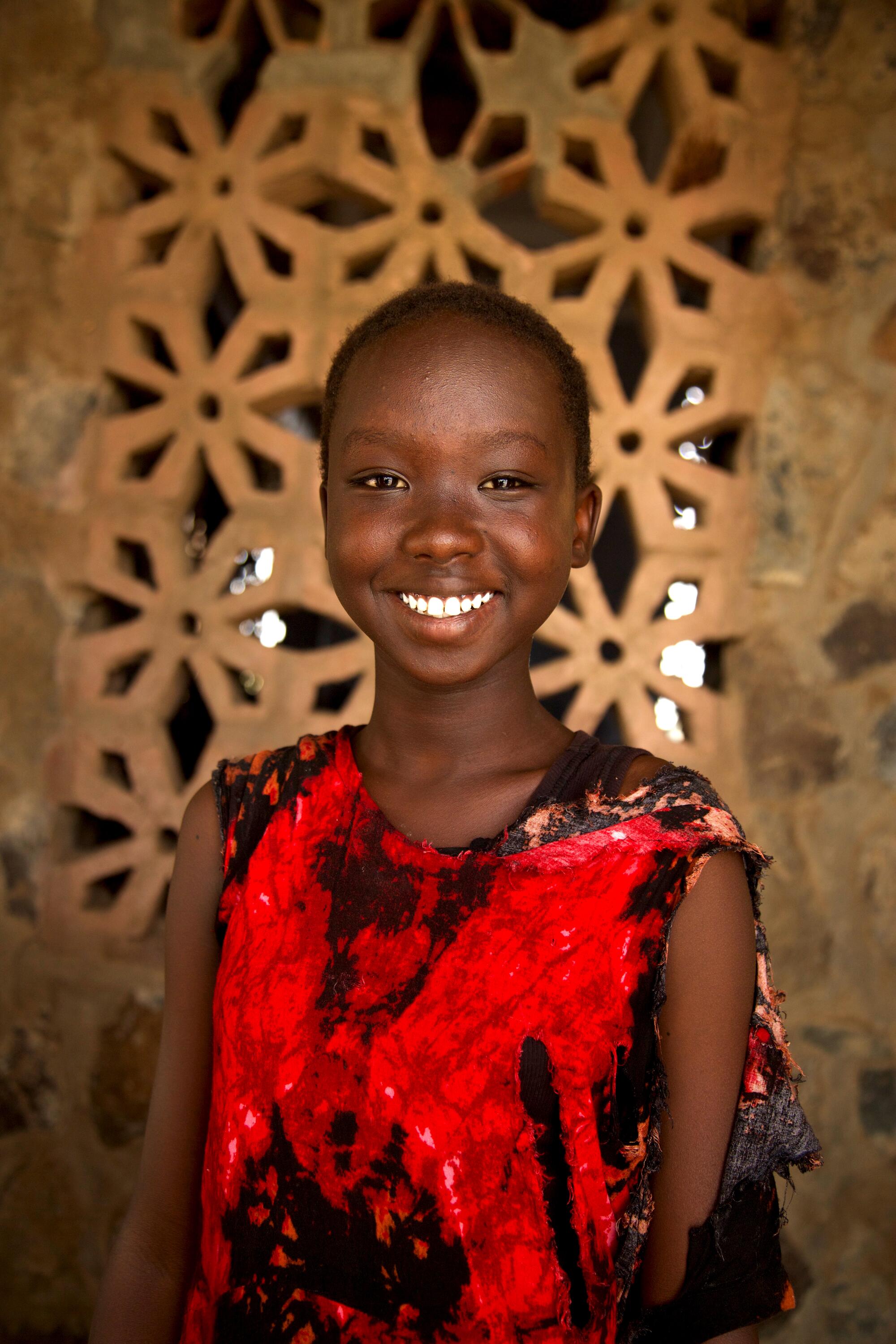 A young girl smiles at the camera for a portrait.