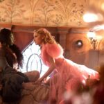 Cynthia Erivo and Ariana Grande sit on a bed in "Wicked."