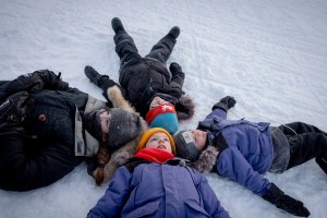 (Clockwise from left) Mia, Colin, Laurent, and Léo Pelletier lay in the snow and look up to the sky in Kuujjuaq, Canada