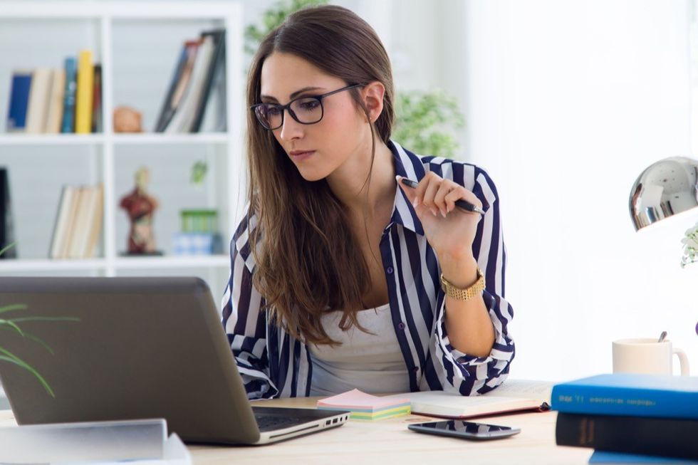 A focused woman sitting at her desk working on a laptop