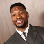 jonathan majors smiling in a suit