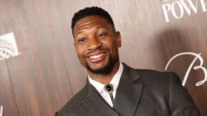 jonathan majors smiling in a suit