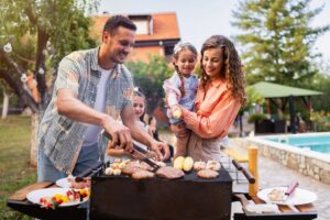 Young couple, wife and husband with daughters grilling on the BBQ