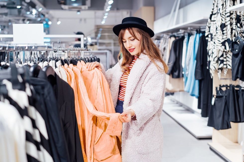 Fashion woman customer looking on peach color shirt in store