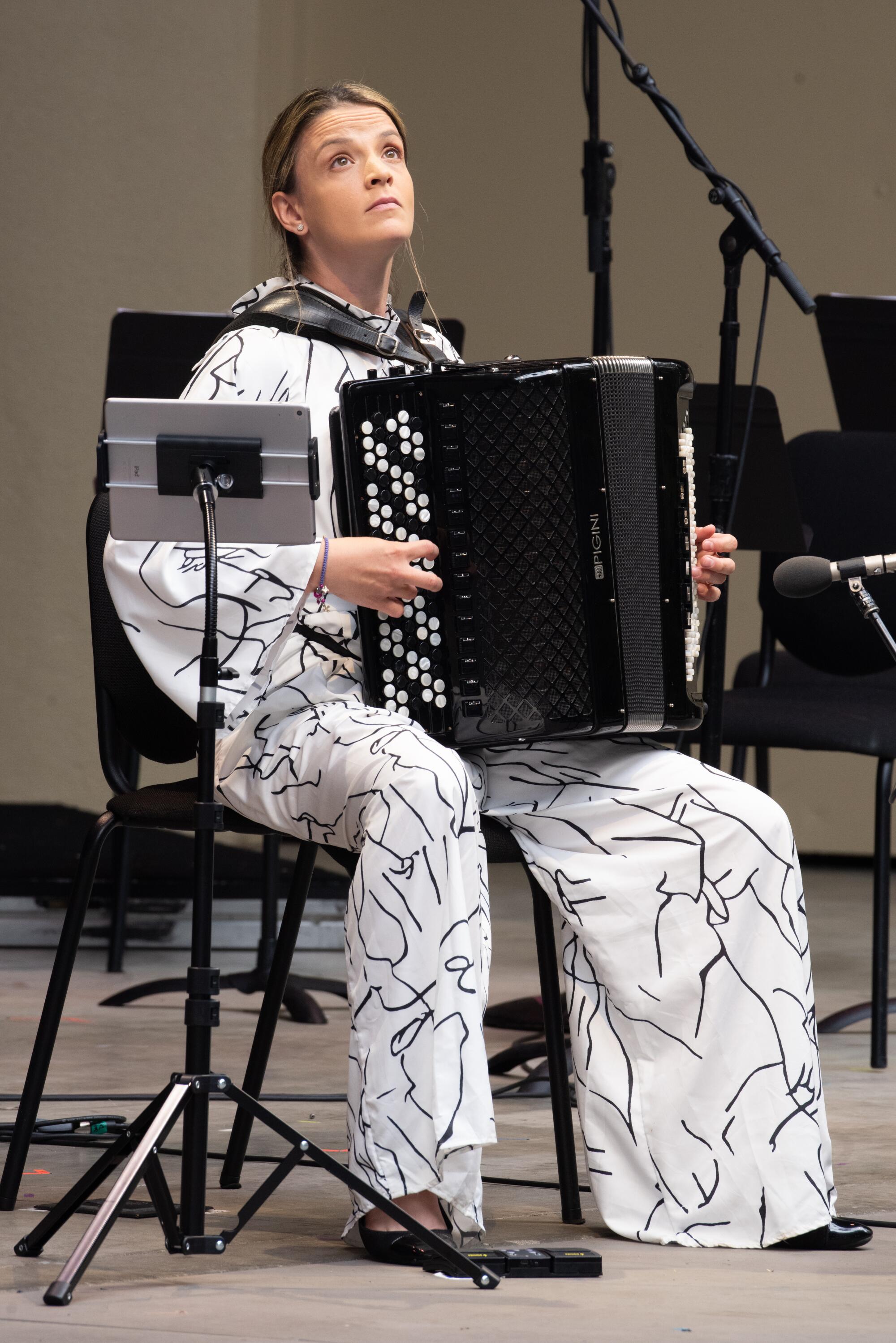 Wearing a voluminous white jumpsuit, Ljubinka Kulisic plays accordion onstage.