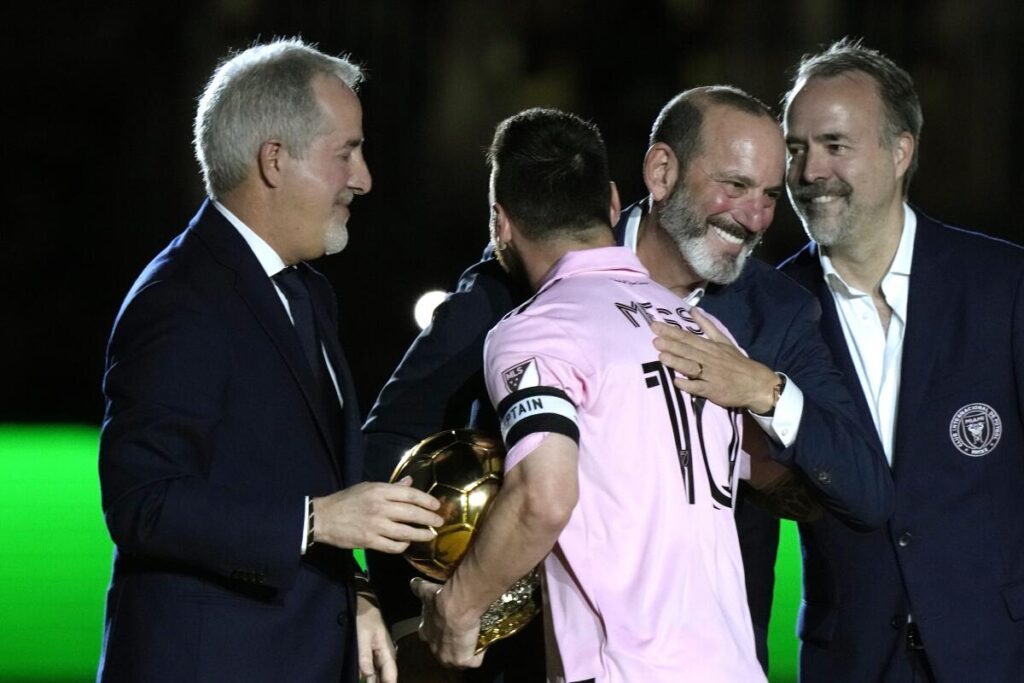 Inter Miami forward Lionel Messi is hugged by MLS Commissioner Don Garber, center right.