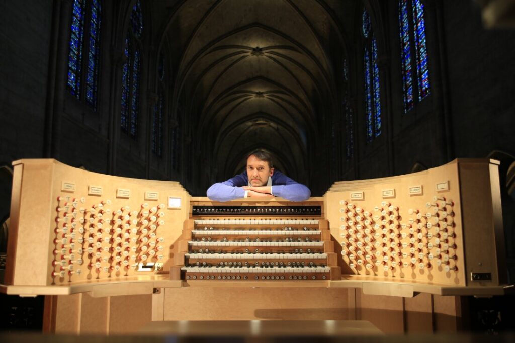 Olivier Latry rests his arms on the refurbished organ at Notre Dame Cathedral.