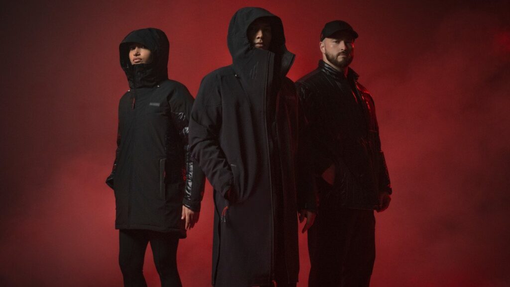 Three people wearing black Columbia Star Wars Darth Vader jackets against a red background