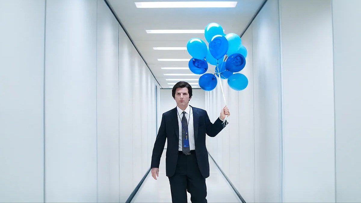 Mark S. (Adam Scott) walks down the long hallway of Lumon with a bunch of balloons with his own face on them in the season 2 trailer for Severance.