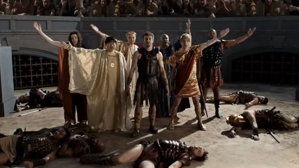 Paul Mescal and SNL cast members standing over dead bodies in a Gladiator II musical sketch