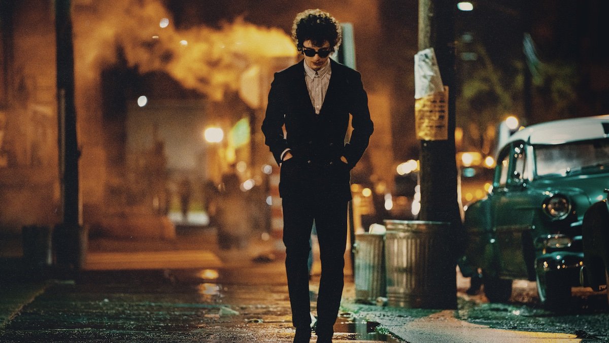 Timothée Chalamet as Bob Dylan walking down a New York City street at night in A Complete Unknown