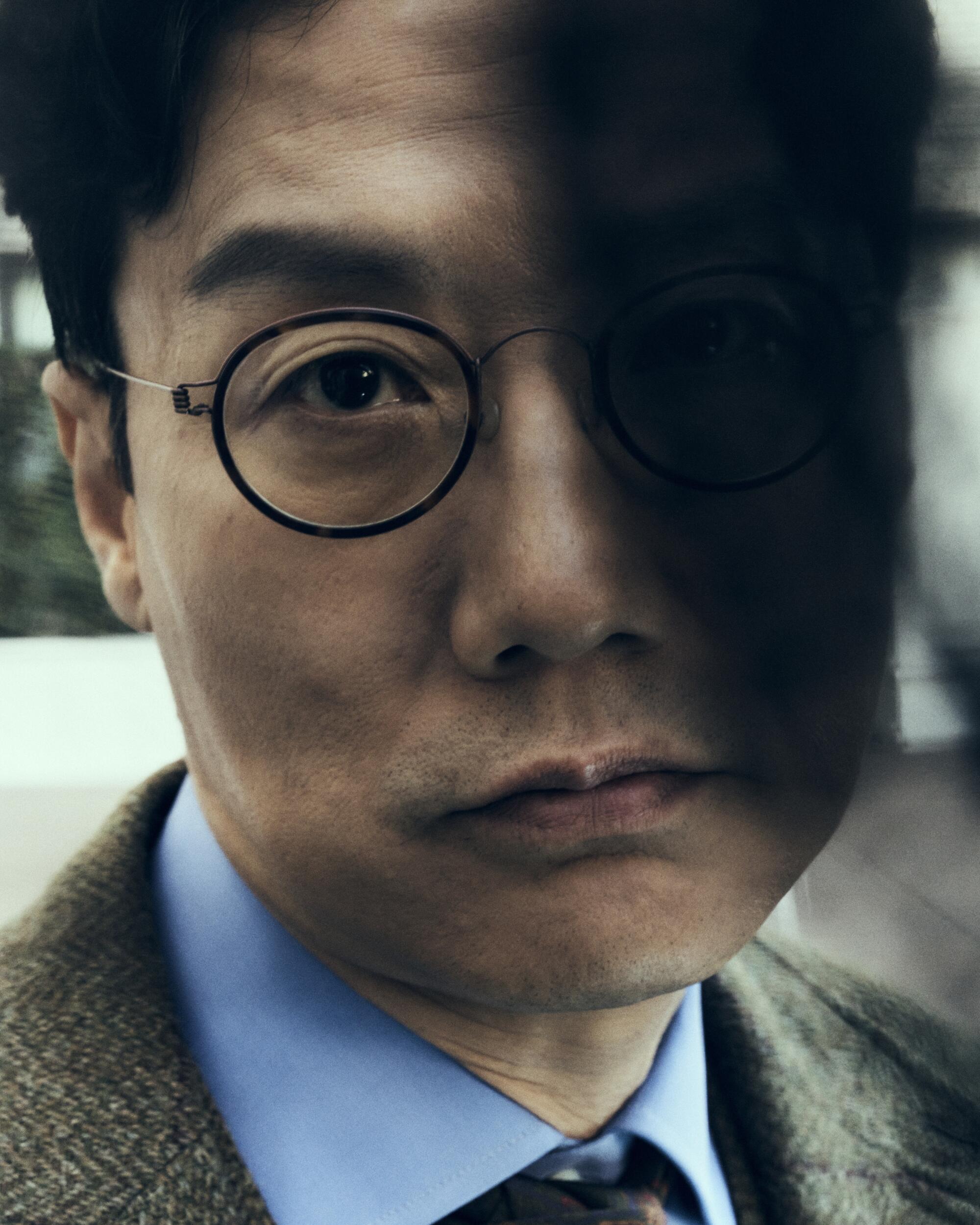 A close-up of Hwang Dong-hyuk with half his face in shadow.