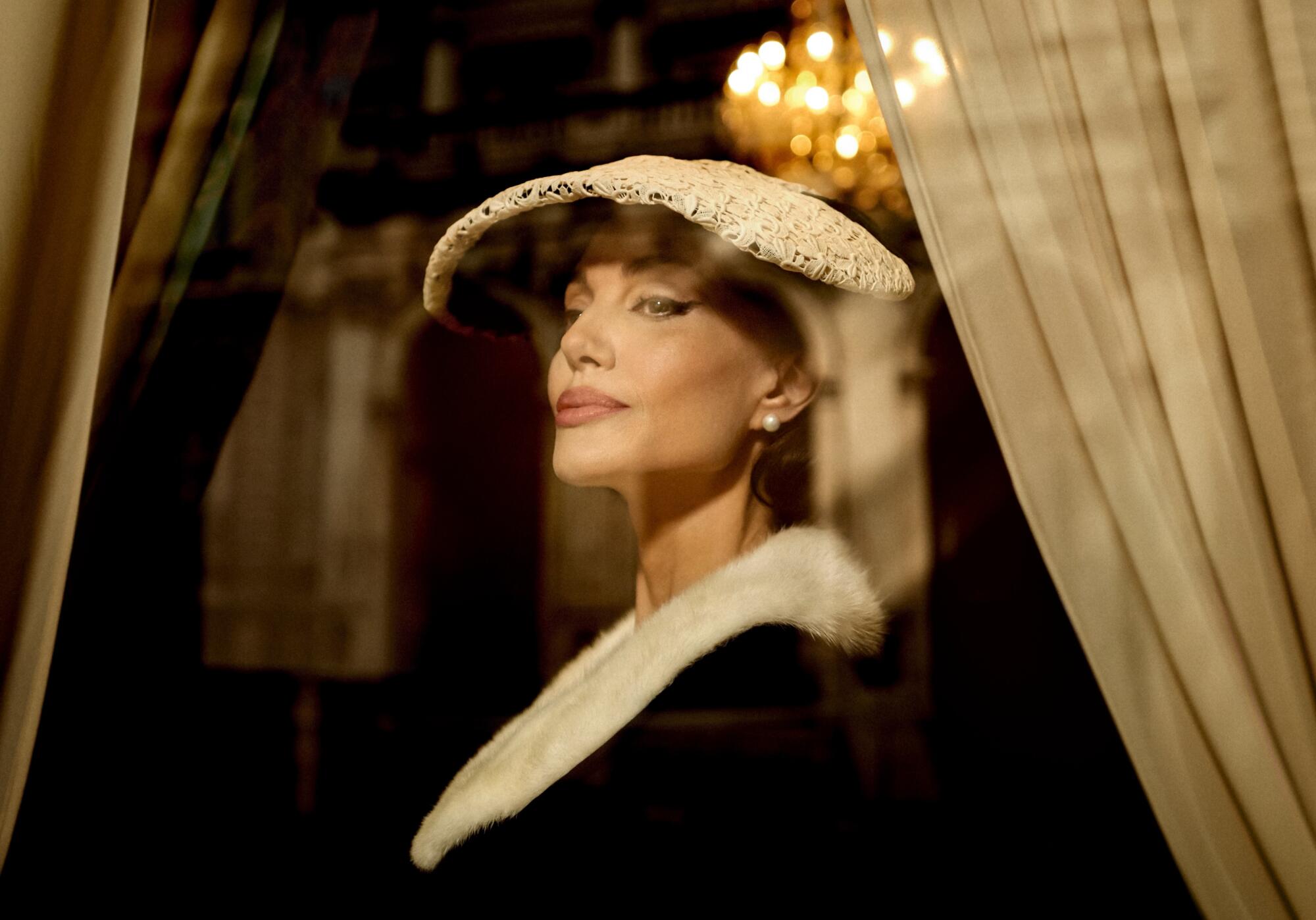 An opera diva smiles cryptically under a fashionable hat.