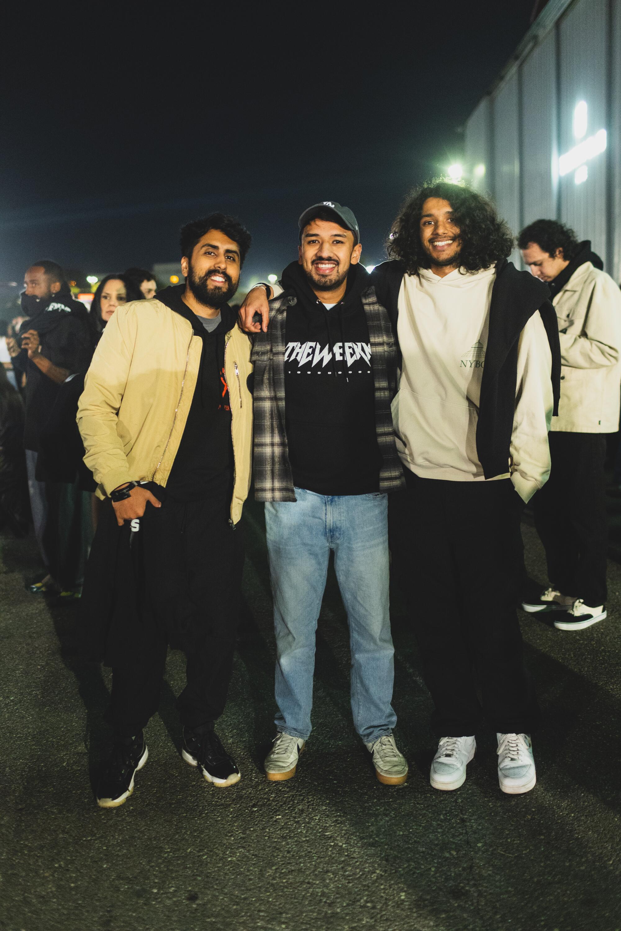 Hamza Akmal, Adeeb Ali and Ameer Ali pose for a photo outdoors at night.