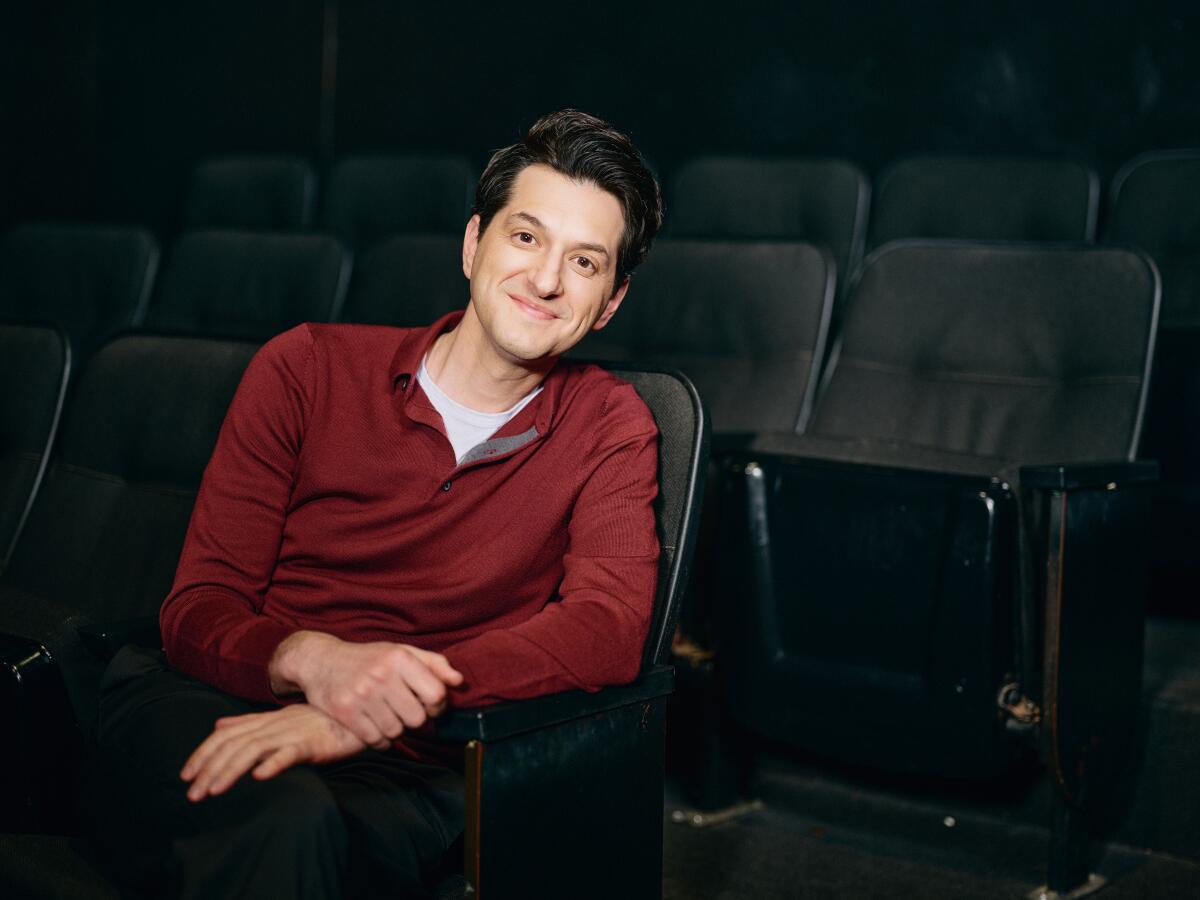 Ben Schwartz sits in a theater seat.