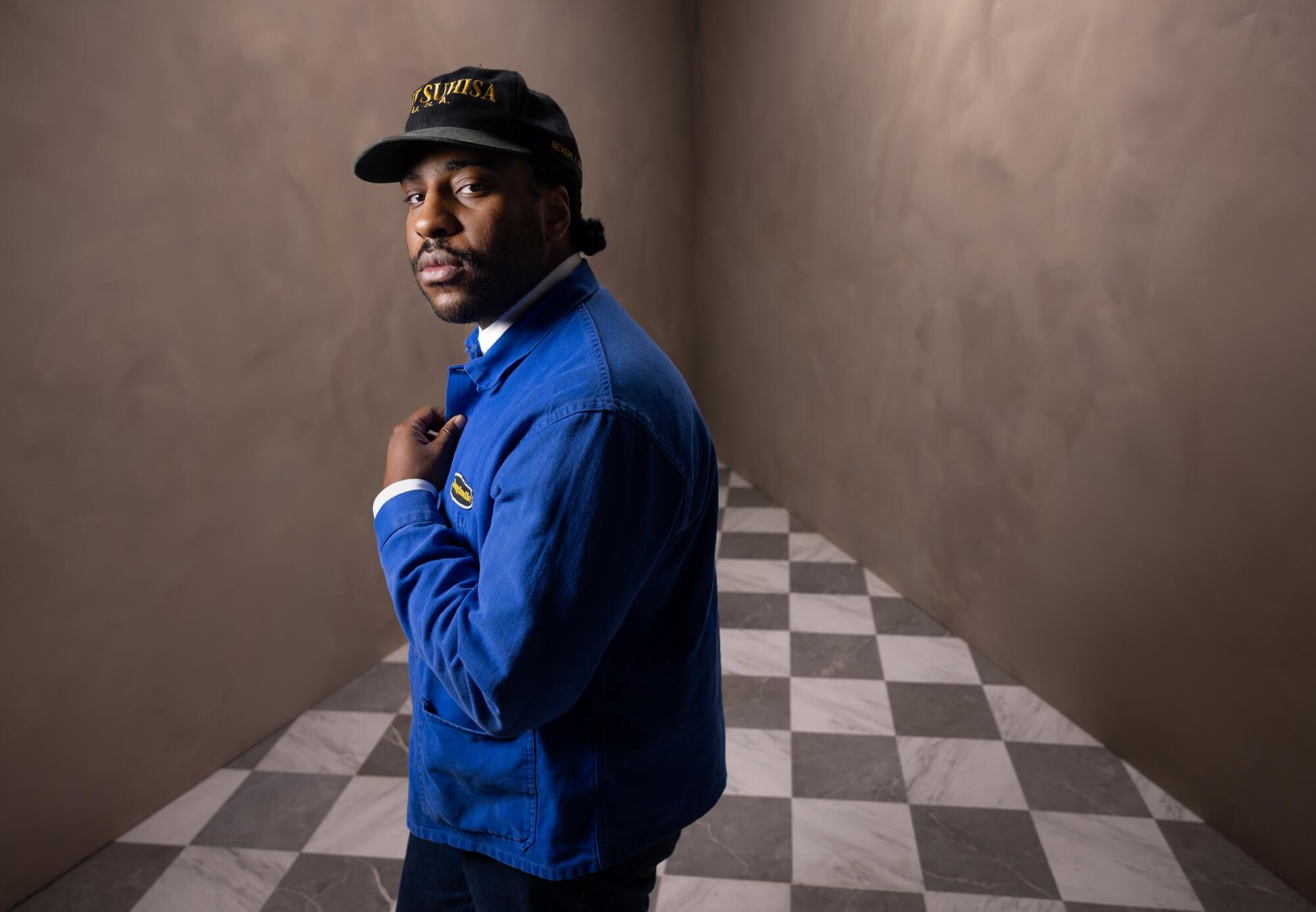  Malcolm Washington stands on a checkered floor for a portrait. 