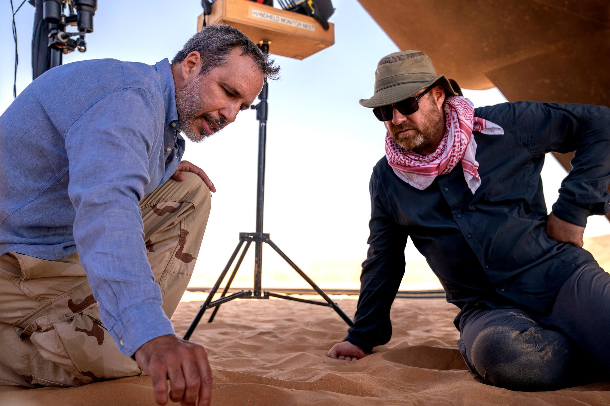 Two men draw in the sand on the set of "Dune: Part Two."