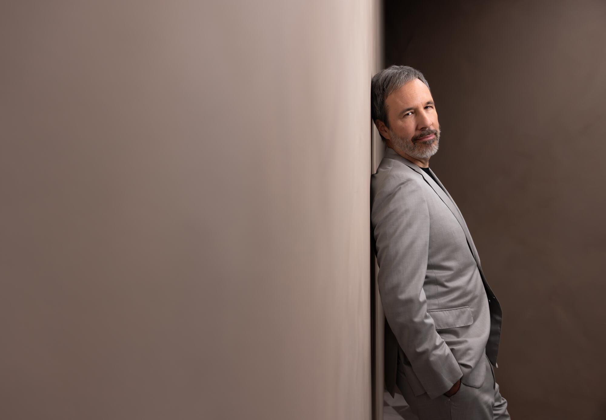  Denis Villeneuve leans against a bare wall for a portrait.