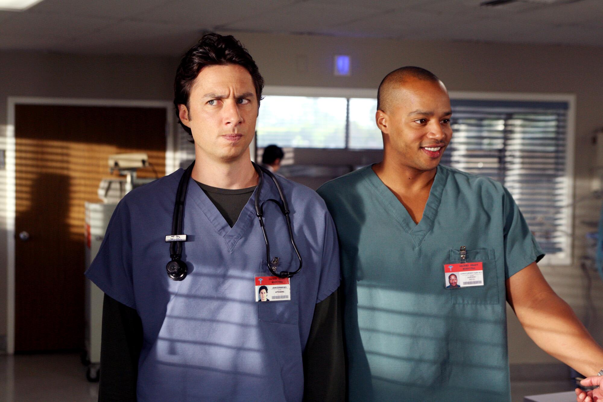 Zach Braff and Donald Faison in medical scrubs stand side by side