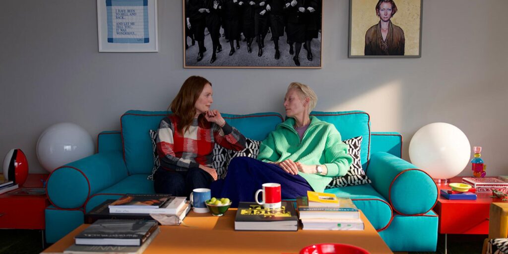 Two women sit on a couch, chatting.