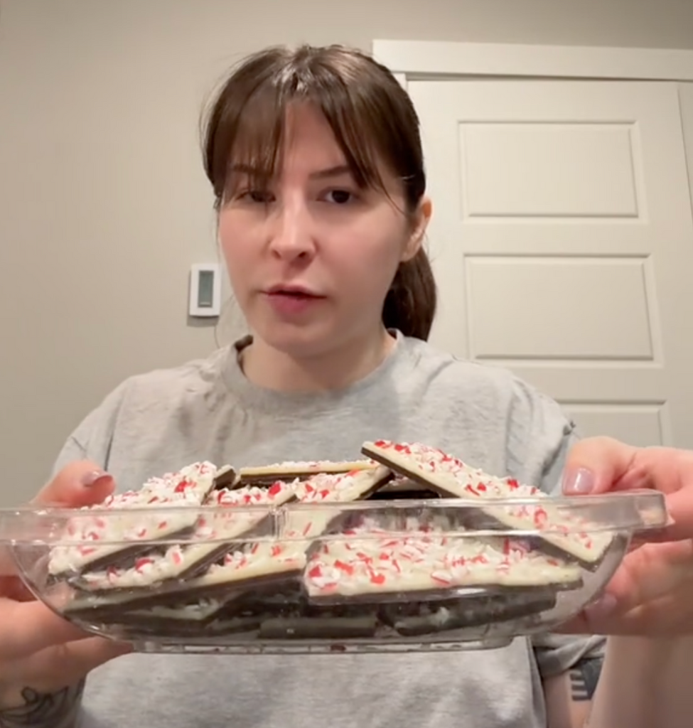 Woman holding up a tray of Costco peppermint bark