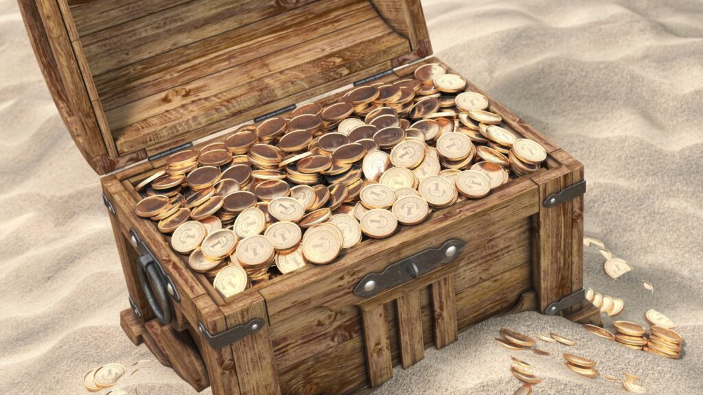 buried treasure chest full of gold coins in the sand