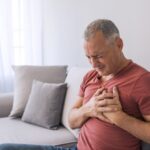 Man holding chest with pain from heartburn.