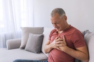 Man holding chest with pain from heartburn.