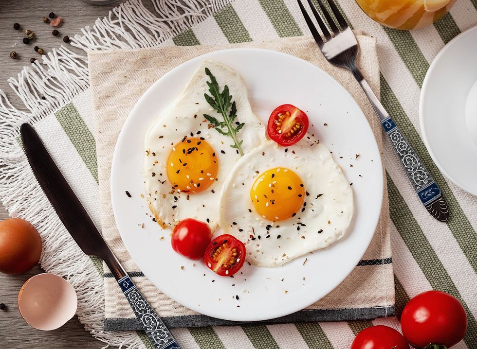 Fried eggs on a plate with cut baby tomatoes