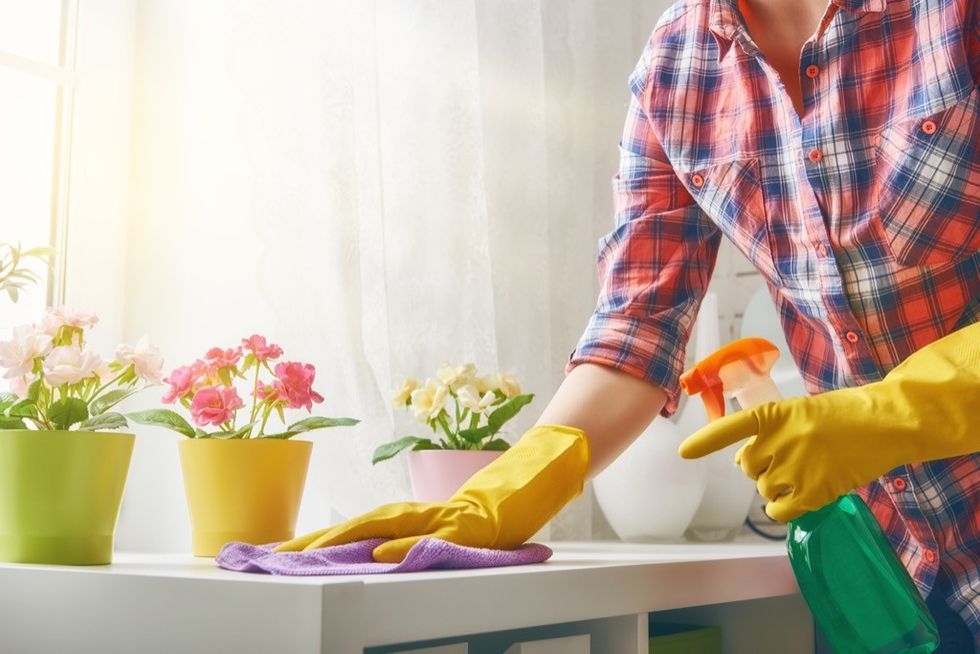 A woman dusting shelves in the bathroom