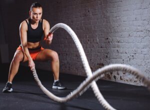 A woman using battle ropes at the gym