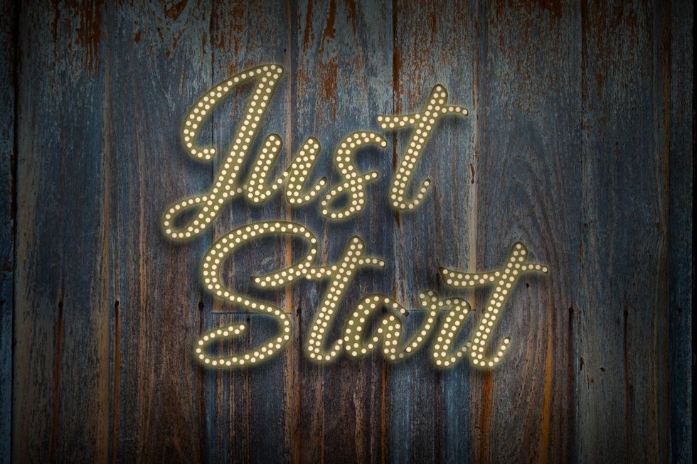 The phrase 'Just Start' illuminated on a wooden background.