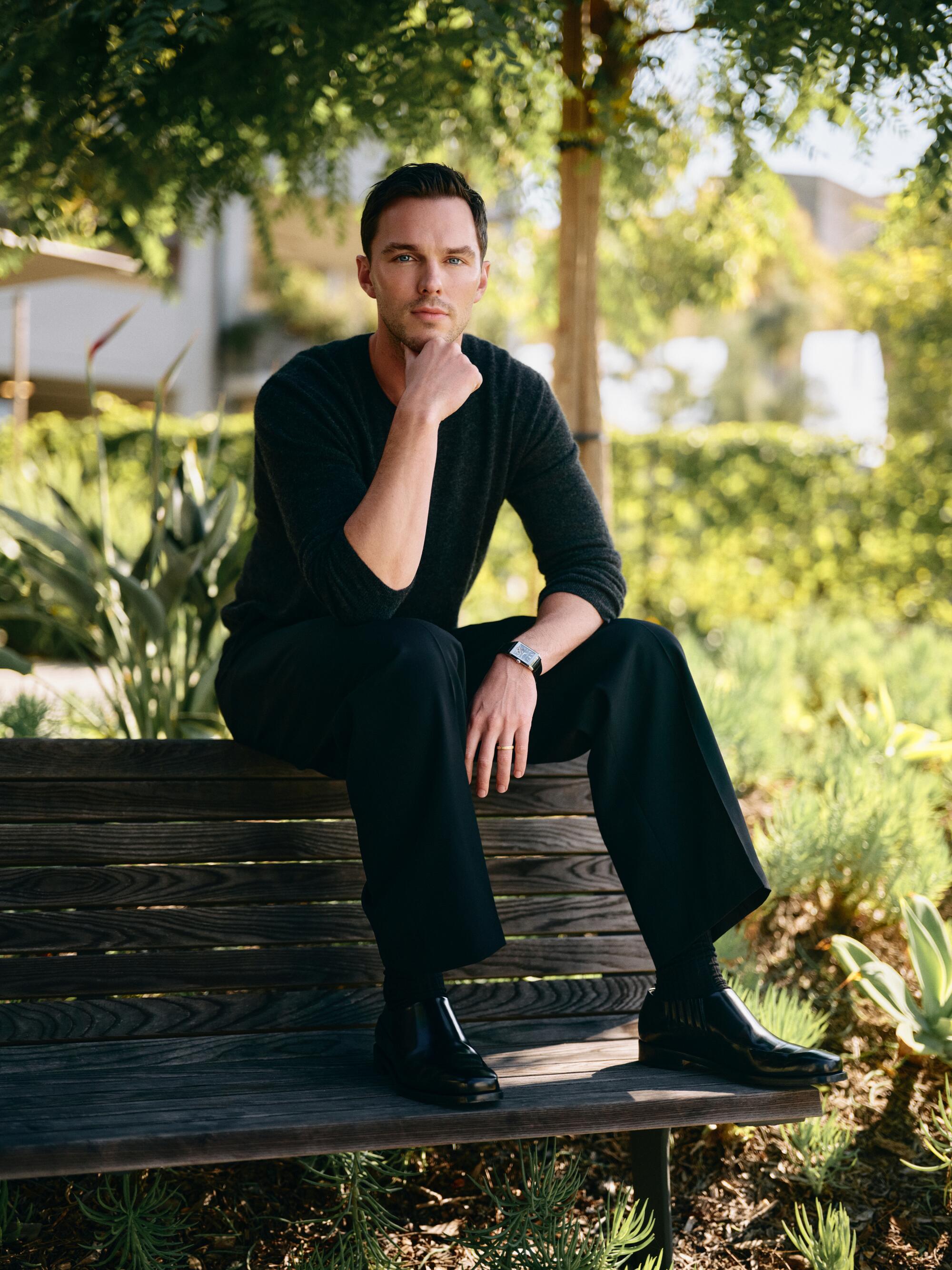  Nicholas Hoult, sitting outside.