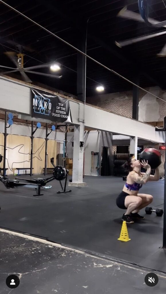 Mattie Rogers is seen doing a squat while using and exercise ball.