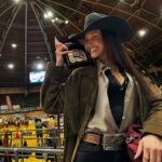 Dressed in a black cowboy hat and green tasselled jacket, Bella Hadid beams with pride as she holds up her medal