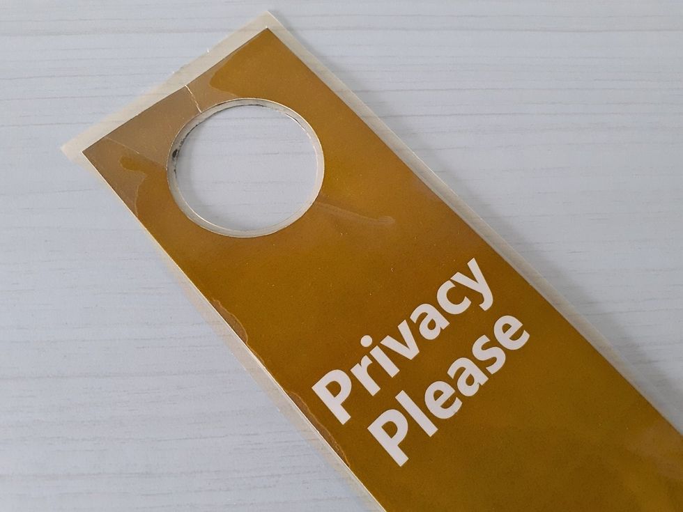 A door sign with the words"'Privacy Please" written o it.