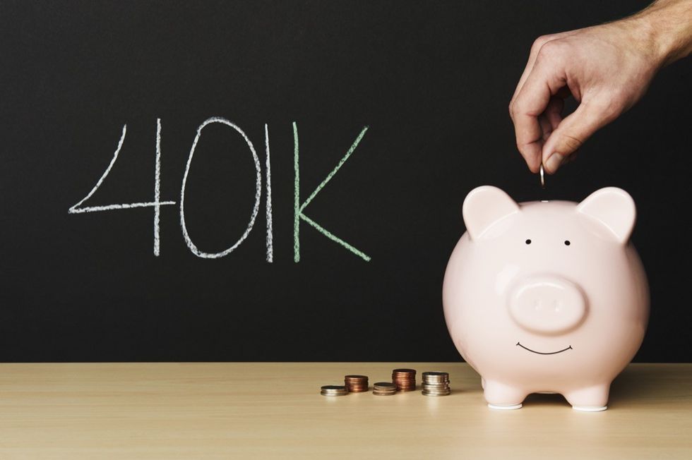 401K written on a chalkboard behind a piggy bank.