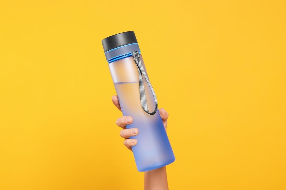 Woman,Holding,Bottle,Of,Drink,On,Orange,Background,,Closeup