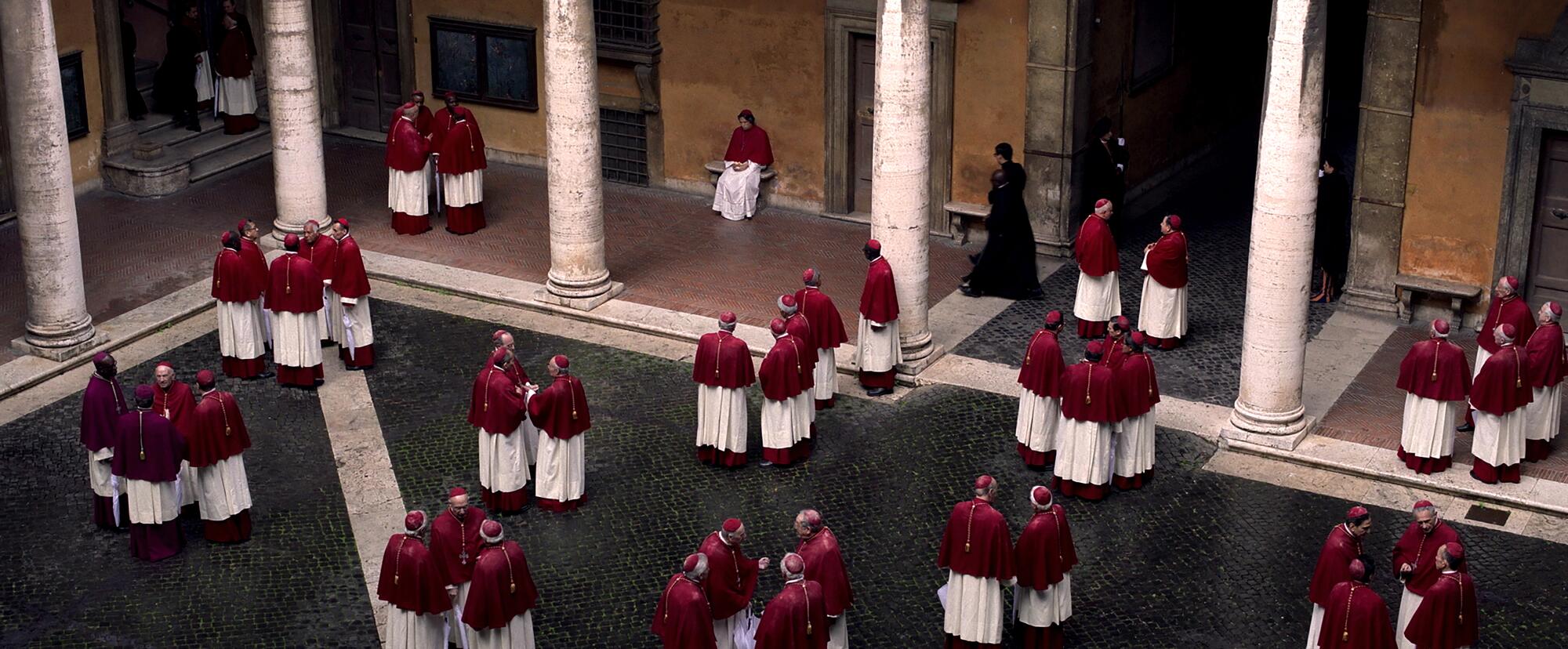 Dozens of cardinals gather in a courtyard, chatting in small groups in "Conclave."