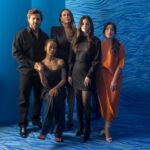 Édgar Ramírez, left, Zoe Saldaña, seated, Karla Sofía Gascón, Selena Gomez and Adriana Paz pose in front of a blue background