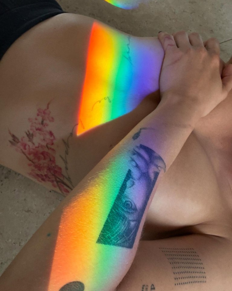 The 32-year-old also flashed her tatts and bare belly as a rainbow light crossed her body