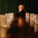 Carol Kane sits at the end of a long table, chin in her hands.