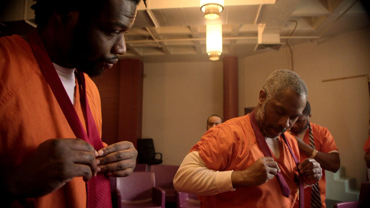 Two men in orange jumpsuits begin to change clothing in "Daughters."