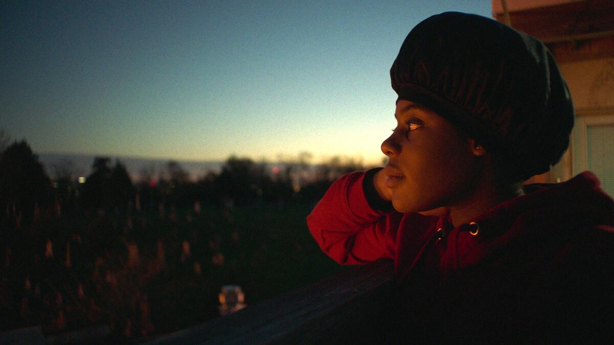 A young woman looks out at a darkening sky in "Daughters."