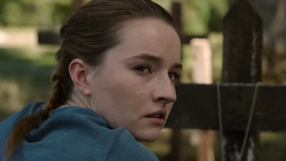 Kaitlyn Dever as a sad Abby kneeling at a grave during a sunny day on The Last of Us season two