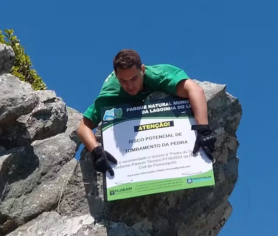 A staff puts up a sign warning people that the cliff rock could collapse