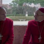 Two cardinals dressed in red discuss papal matters.