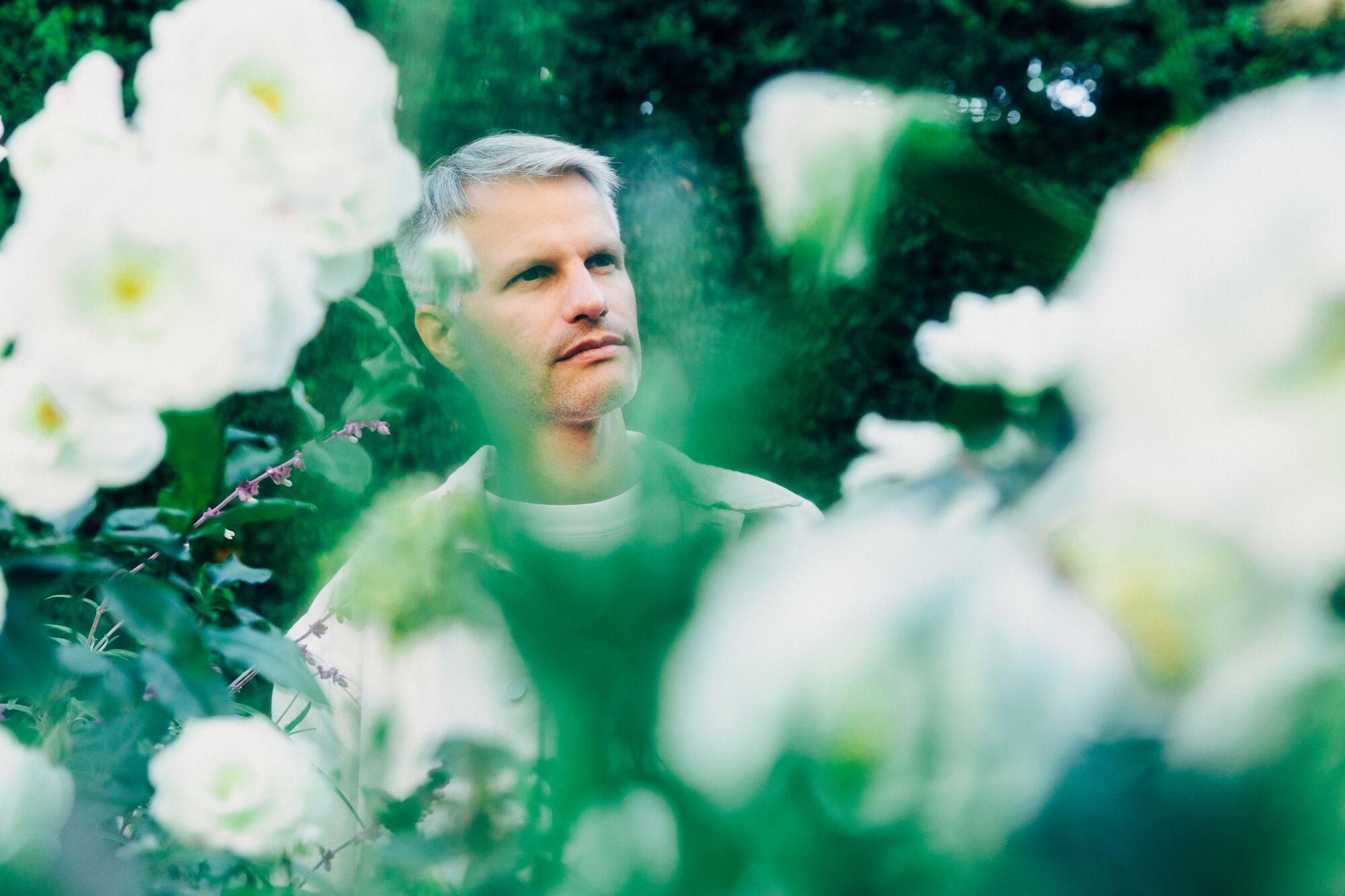 Markus Förderer stands outside amid flowers for a portrait.