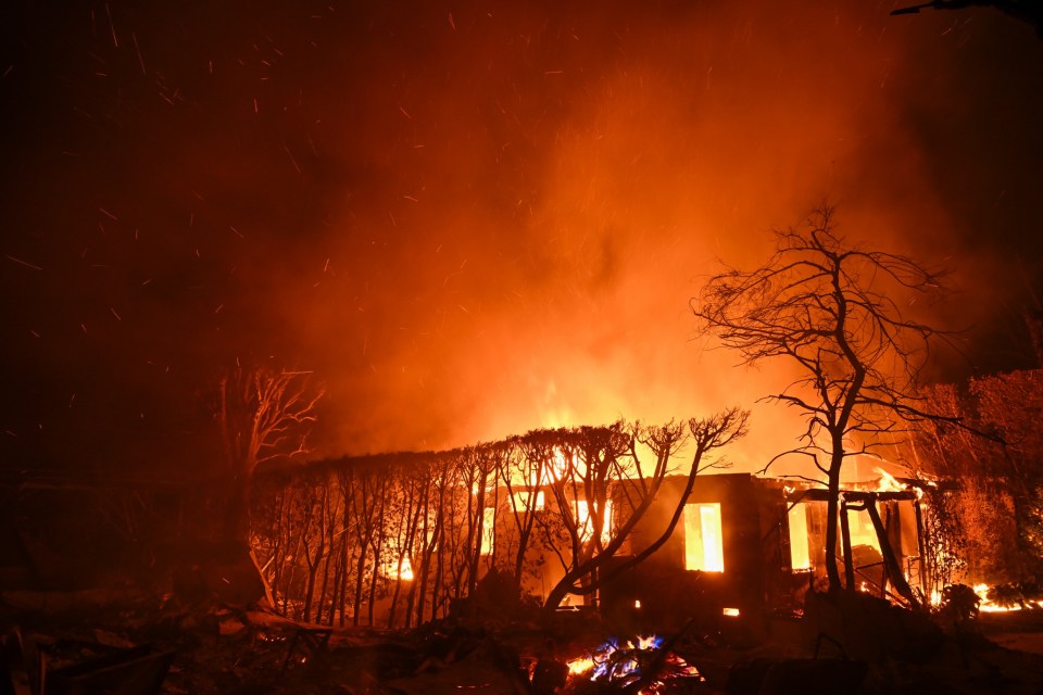 CALIFORNIA, UNITED STATES - JANUARY 8: A house in on fire as residents try to escape the site in Pacific Palisades, California, Los Angeles, United States on January 8, 2025. A fast-moving wildfire has forced 30,000 people to evacuate, with officials warning that worsening winds could further escalate the blaze. (Photo by Tayfun Coskun/Anadolu via Getty Images)